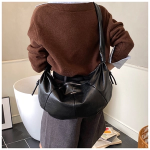 Detailed view of a black large crescent crossbody bag with side drawstring accents