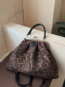 Retro leopard print tote bag with silver metal clasp and black leather straps in sunlight