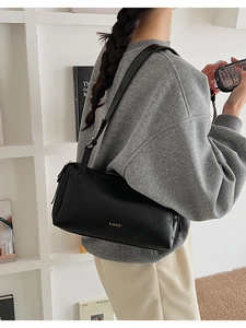 Dettaglio della borsa a cuscino nera minimalista con trama opaca e logo dorato