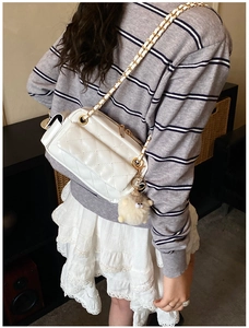 Détail du sac bandoulière blanc matelassé avec chaîne dorée et breloque mouton