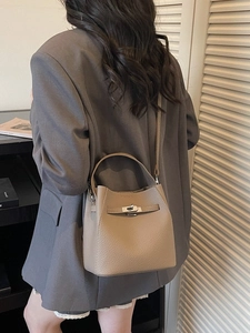 Minimalist khaki leather bucket bag with top handle and crossbody strap for work