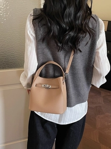Elegant camel leather bucket bag with silver twist lock shown on model in a soft room