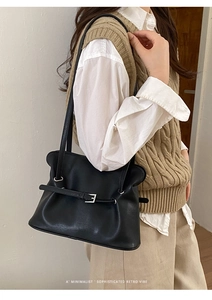 Détail d'un cabas en cuir noir minimaliste avec une ceinture décorative et boucle argentée
