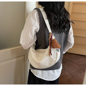 Detailed shot of white hobo bag with heart pendant and colorful tassel on model
