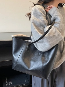 Minimalist black leather tote bag with elegant texture worn by model on shoulder