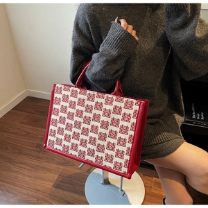 Détail du sac cabas de mariée rouge avec motifs Xi et garnitures en cuir
