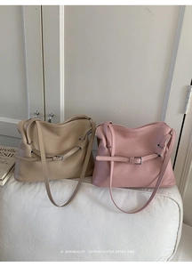 Gros plan sur des sacs cabas plissés kaki et rose avec boucles sur un canapé blanc