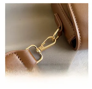 Dettaglio dei ganci in metallo dorato e della trama in pelle litchi della borsa a tracolla