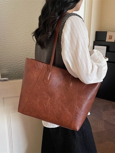 Vintage brown leather tote bag with pleated texture and dual straps on female model