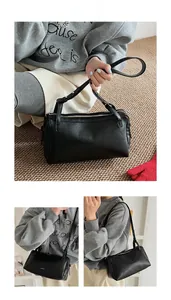Dettaglio di borsa a cilindro nera con zip dorata e tracolla in pelle regolabile