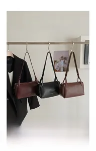 Borse baguette in pelle minimaliste in bordeaux, nero e marrone appese a un'asta metallica