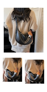 Detail of a matte black crescent crossbody bag featuring a brown plush heart charm