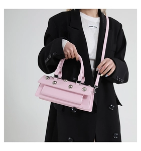 Détail du sac en similicuir rose avec clous argentés et fine bandoulière amovible