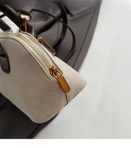 Detailopname van beige suède en bruin leer met een hoogwaardige goudkleurige ritssluiting