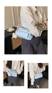 Detalle de bolso acolchado azul claro con cadena dorada y colgante de pompón suave