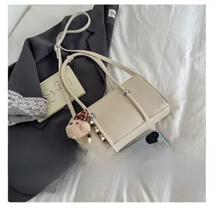 Detail of cream baguette bag with lychee grain leather, silver beads and plush charm