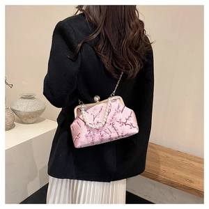 Pink silk evening bag with cherry blossom embroidery and pearl handle worn by a model