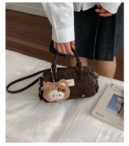 Detail of dark brown vintage Boston bag with plush charm and golden metal hardware