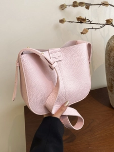 Chic pink textured leather crossbody bag with top handle and gold hardware in hand
