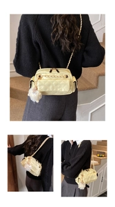 Detalle de bolso acolchado amarillo crema con rombos, cadena metálica y colgante suave