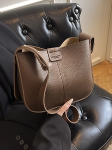 Deep brown pebble grain leather bucket bag with wide shoulder strap and elegant silhouette