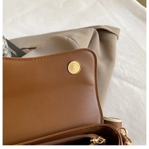 Dettaglio della chiusura magnetica dorata e della tasca interna con zip della borsa marrone