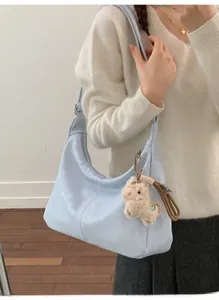Detail of light blue leather hobo bag with a cute alpaca plush keychain accessory
