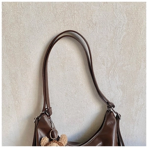 Detail of dark brown tote bag with contrast stitching and plush bear charm