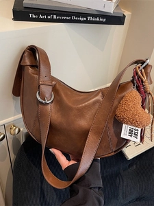 Retro dark brown leather crescent bag with shoulder strap and plush heart charm