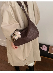 Detail of vintage brown crossbody bag with silver buckle and cute white lamb charm