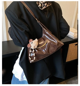 Detail of vintage brown leather hobo bag with gold buckle and plush doll accessory