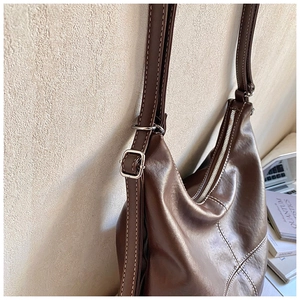 Detailed view of dark brown faux leather tote with cream stitching and zipper closure