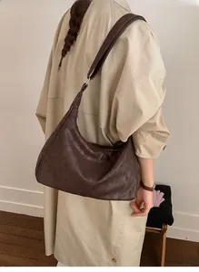 Hobo shoulder bag in dark brown faux leather shown in a lifestyle commuter setting