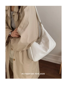 Side view of white hobo bag worn with a beige trench coat for a minimalist look