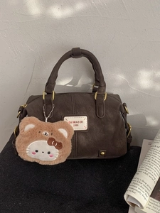 Dark brown leather Boston bag with plush bear charm and vintage golden hardware detail