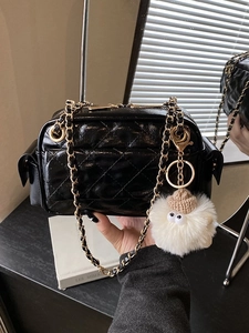 Sac bandoulière noir matelassé avec chaîne dorée et breloque en peluche blanche