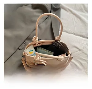 Internal capacity of light pink leather square bag showing phone and cosmetic accessories