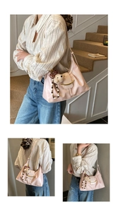 Detail of pink crescent shoulder bag with golden hardware and plush bear charm