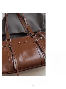 Detail of brown oil-wax leather tote bag showing glossy texture and metal rivet accents