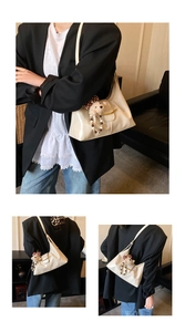 Detail of cream faux leather shoulder bag with gold clasp and plush bear charm