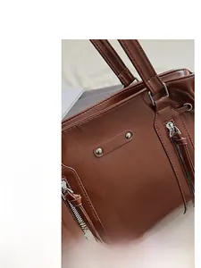 Close-up of shiny caramel oil wax leather tote featuring silver zippers and reinforced stitching