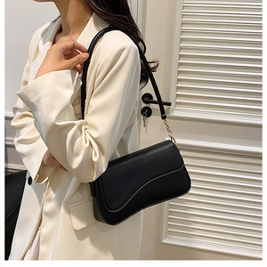 Dettaglio di una borsa a sella vintage nera con catena dorata e tracolla in pelle