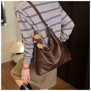 Close-up of brown PU leather tote bag with contrast stitching and plush bear charm