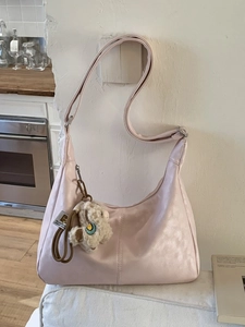 Pink crescent shoulder bag with alpaca charm shown in a cozy home setting