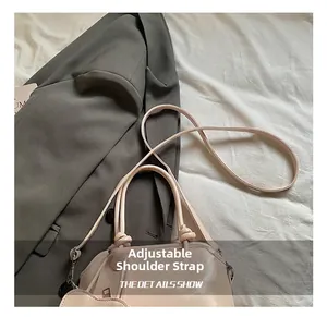 Detail showing adjustable shoulder strap on minimalist pink shell bag with knot handle