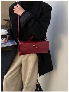 Détail du sac baguette en cuir verni rouge foncé avec fermoir en métal doré torsadé