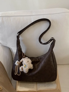 Retro dark brown leather tote bag with alpaca charm on a white sofa backdrop