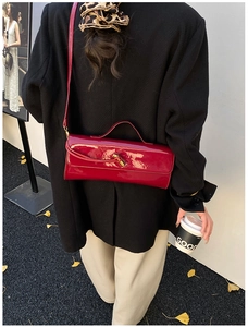 Détail du sac à main en cuir verni rouge avec fermoir doré et fine bandoulière chic