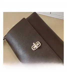Detailed view of shiny silver twist lock on dark brown textured leather crossbody bag