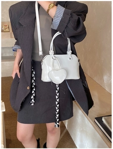 Detail of white glossy leather handbag with heart-shaped coin purse and silver buckle